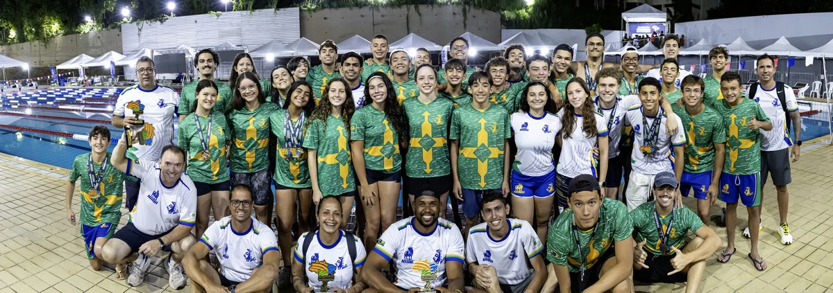 Delegação do Distrito Federal reunida à beira da piscina em cerimônia noturna